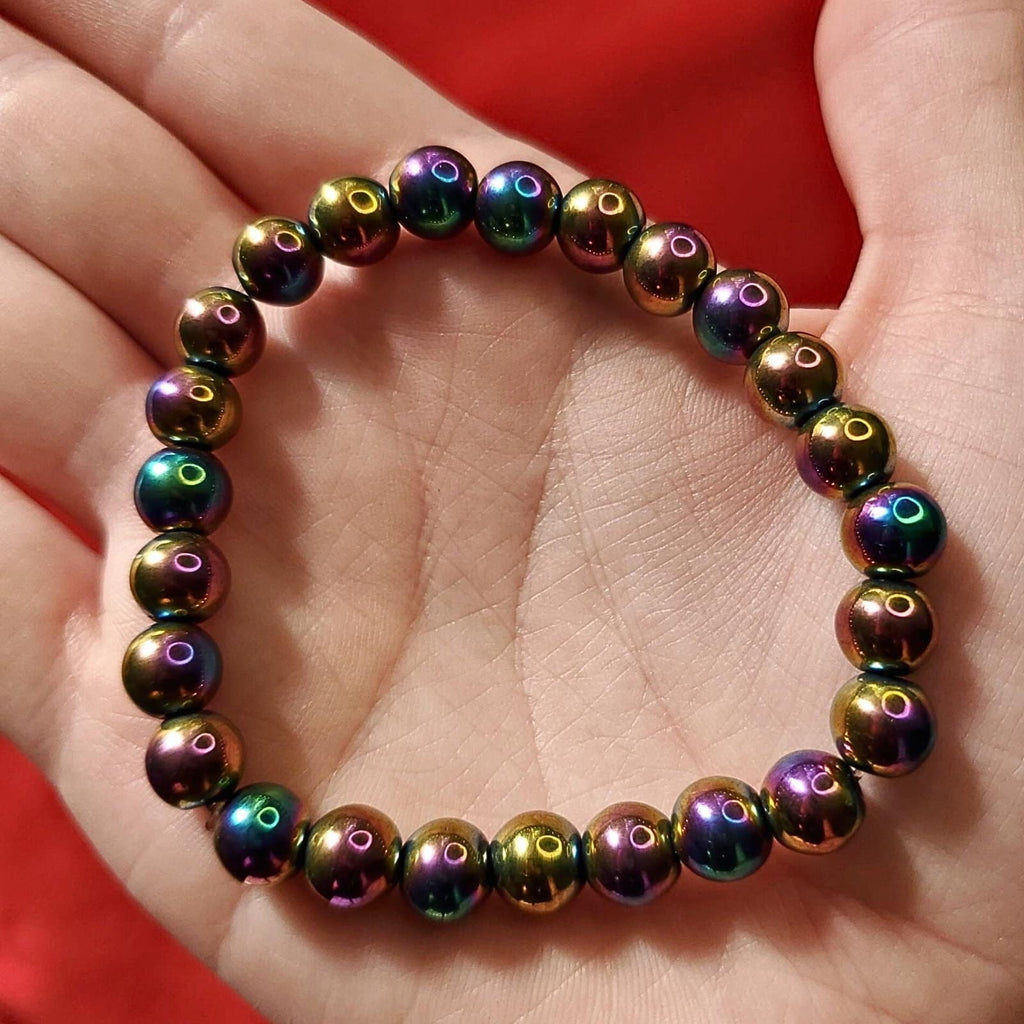 Rainbow hematite beaded bracelet held in hand with multicolor metallic beads by Corona Charms
